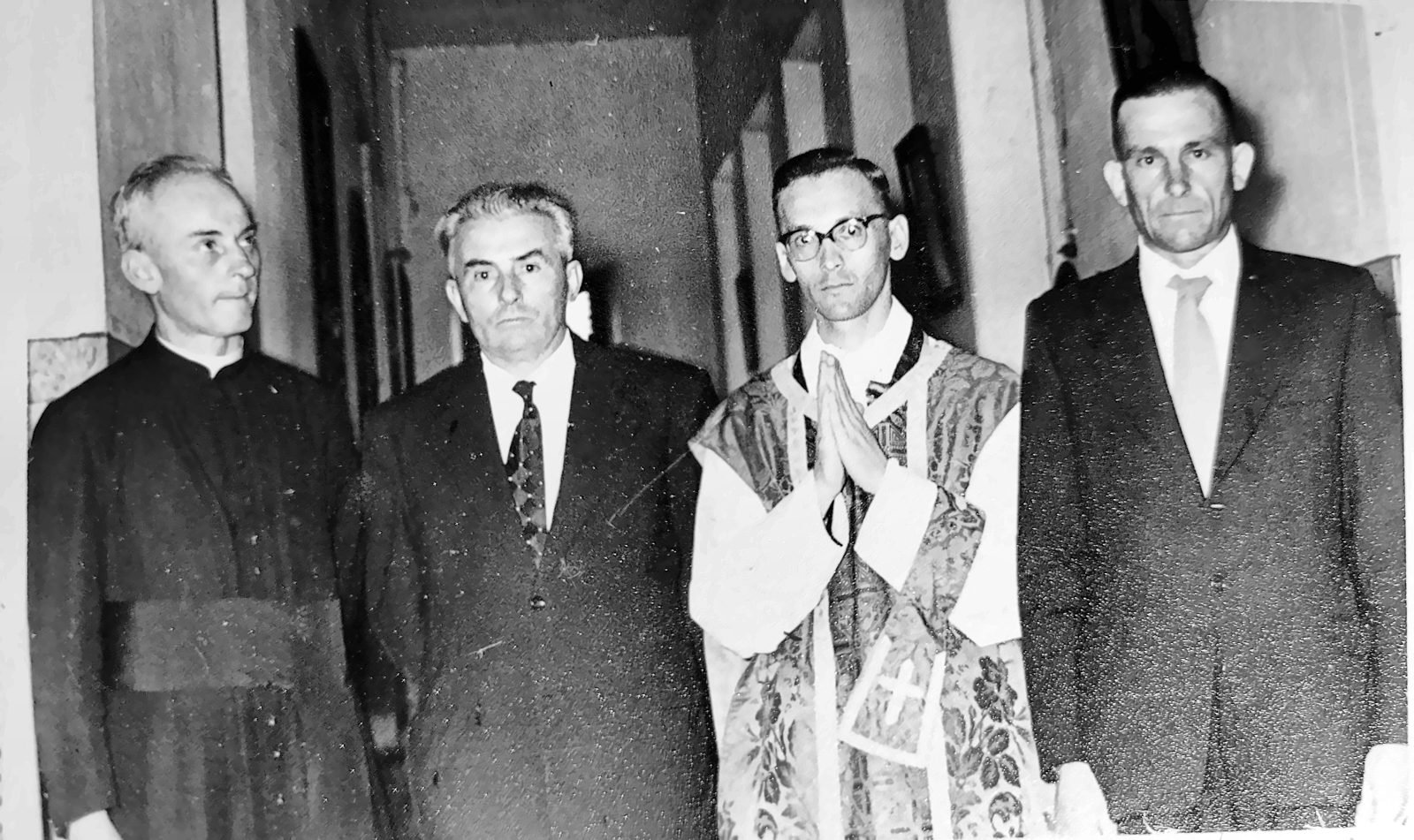Quatro homens, dois deles religiosos, em corredor de igreja
